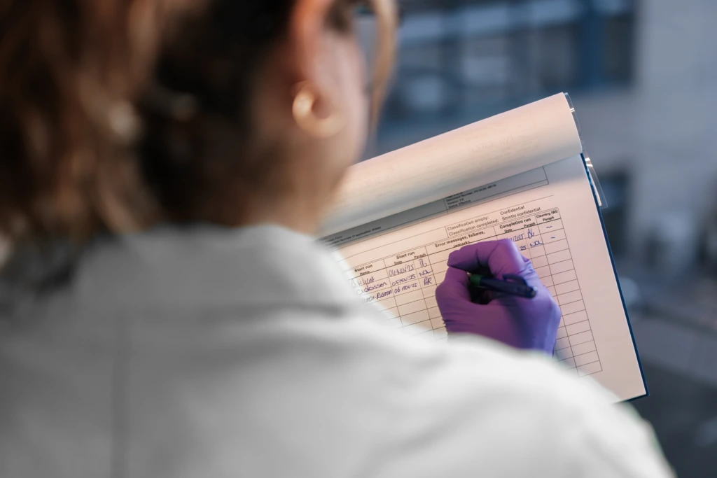Close up taken over shoulder of female scientist taking notes
