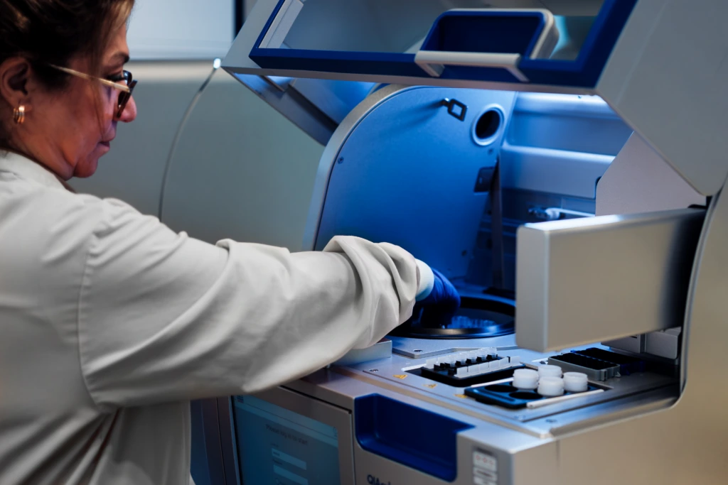 Medium close up of female scientist operating a laboratory analyzer machine during sample preparation A