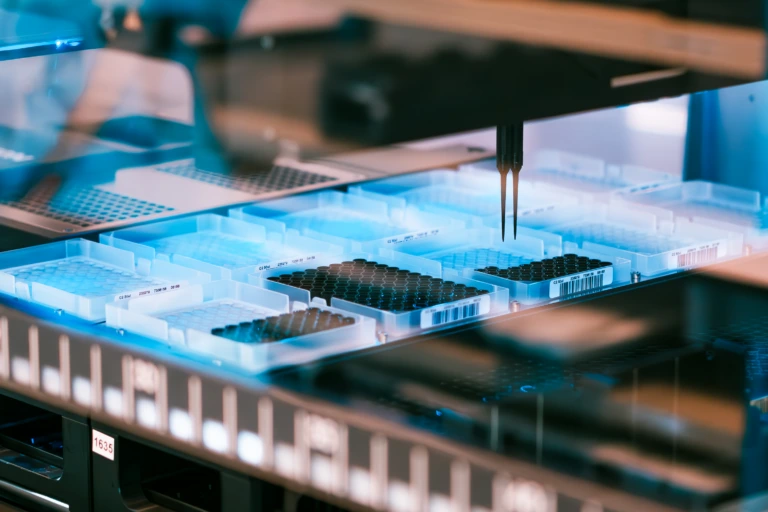 Close up of automated pipetting system dispensing samples into a laboratory well plate A