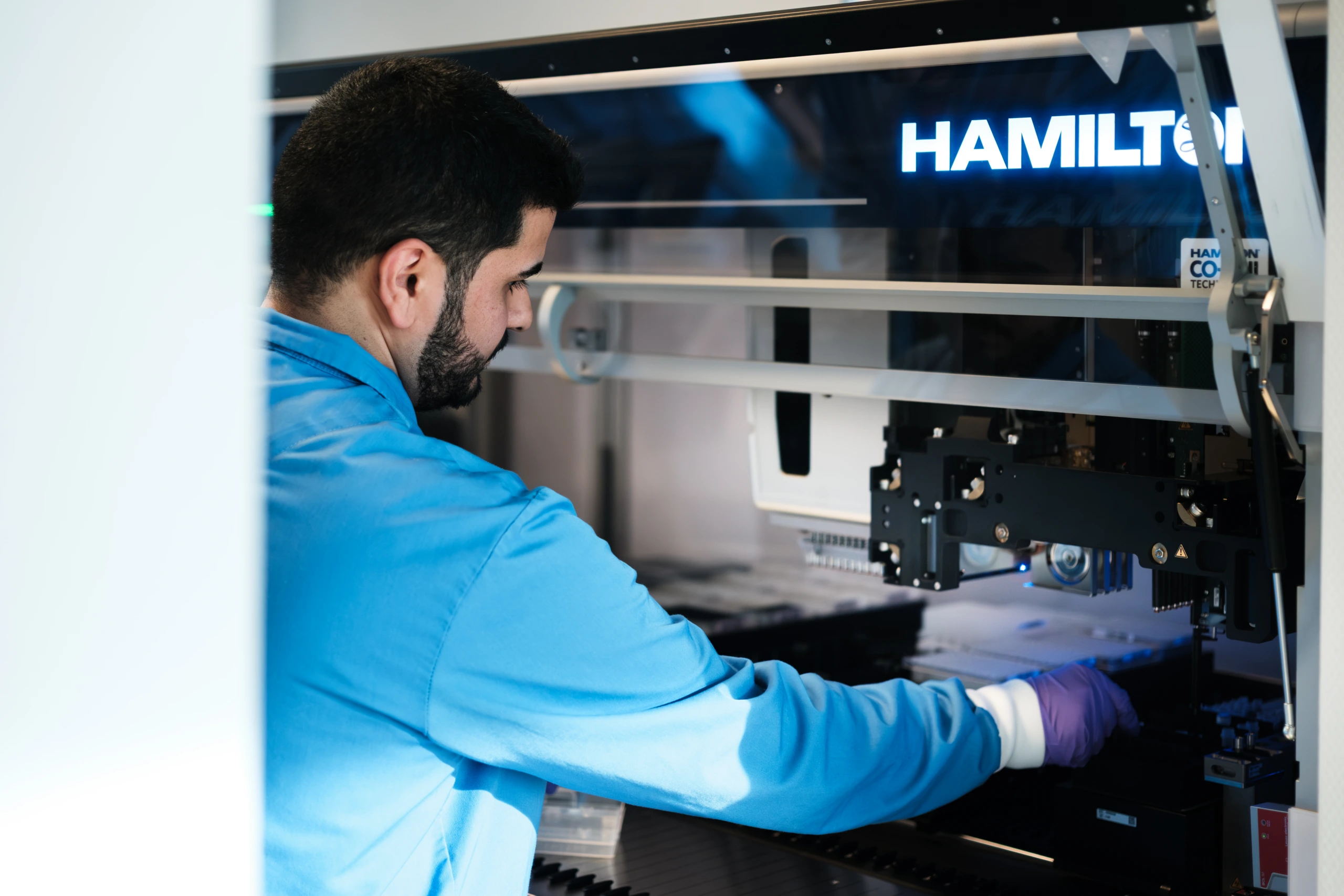 Medium close up of male scientist operating a Hamilton laboratory automation system.