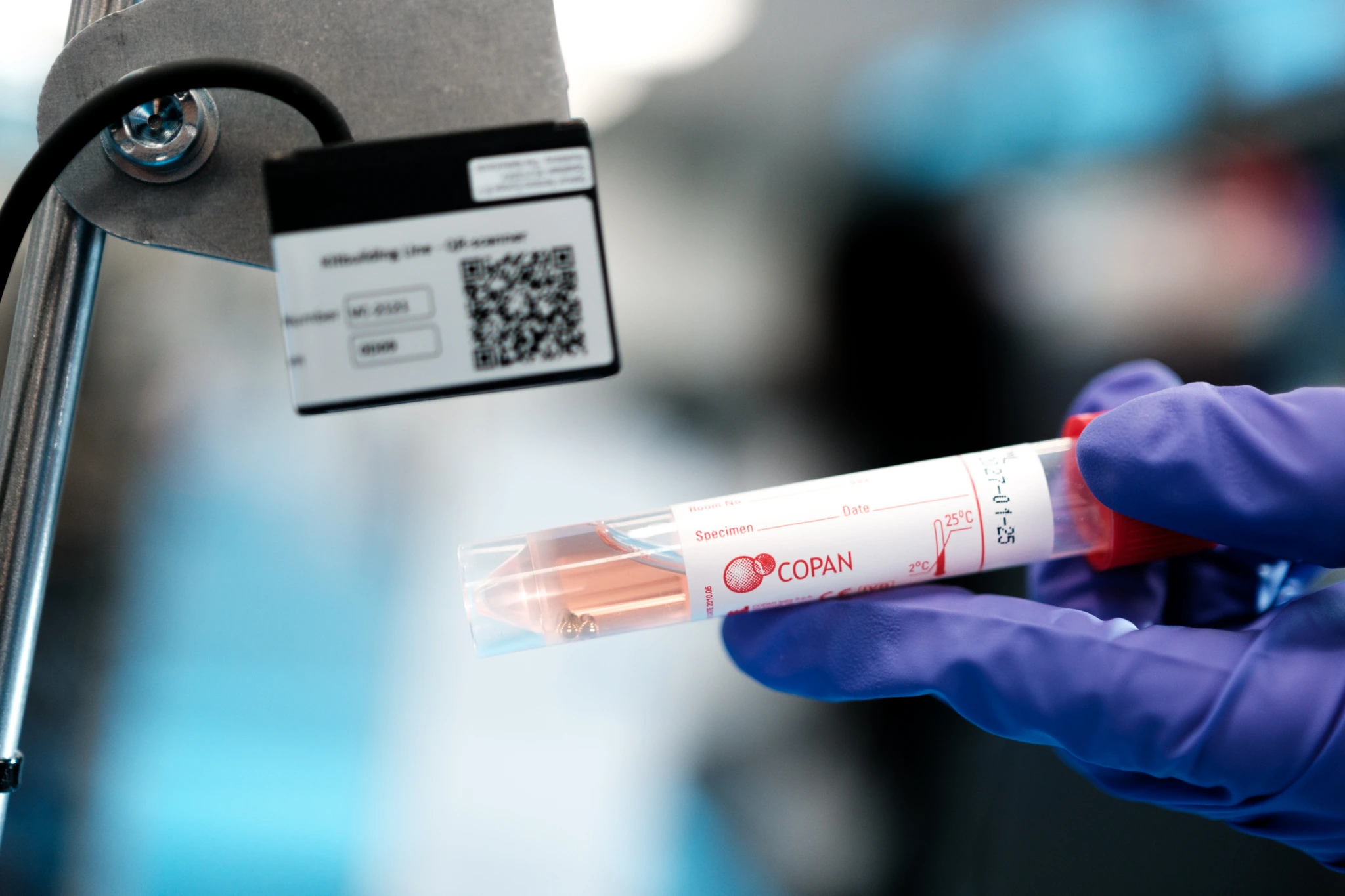 Extreme close up of purple gloved hands scanning sample tube on packing line