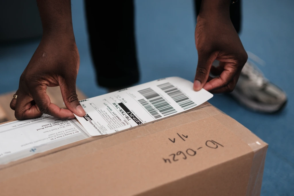 Close up of hands placing label on shipping box