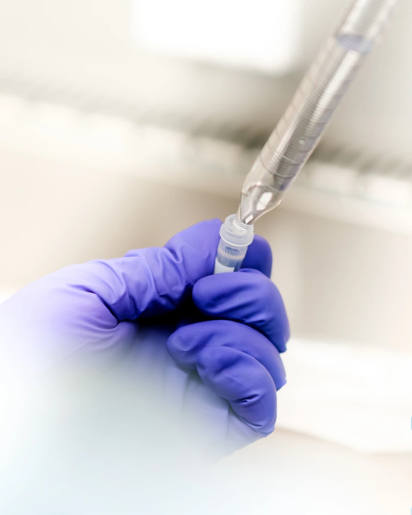Close up of vial and syringe held by gloved laboratory hand