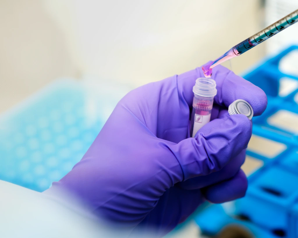 Scientist pipetting sample into laboratory tube