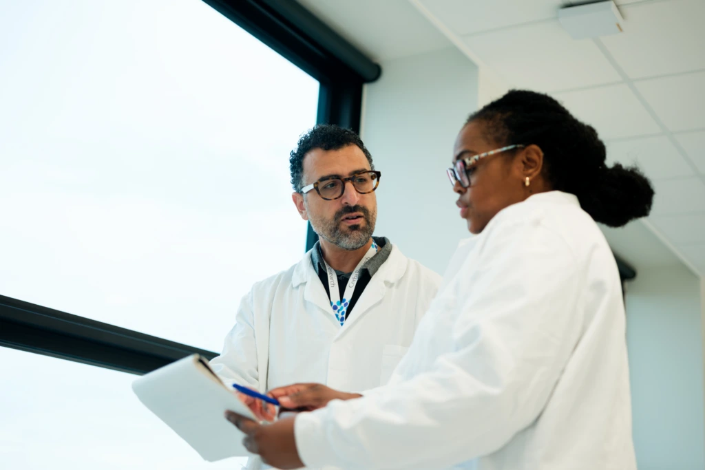 Scientists discussing clipboard beside laboratory workspace