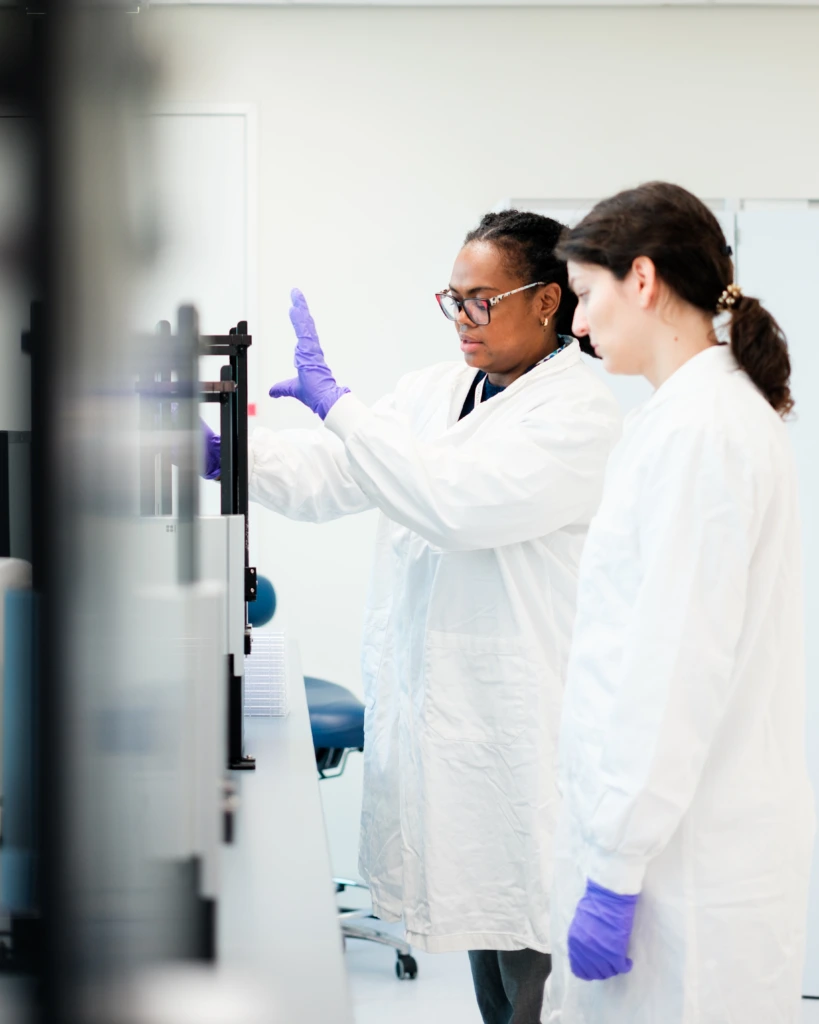 Scientists operating automated liquid handling system