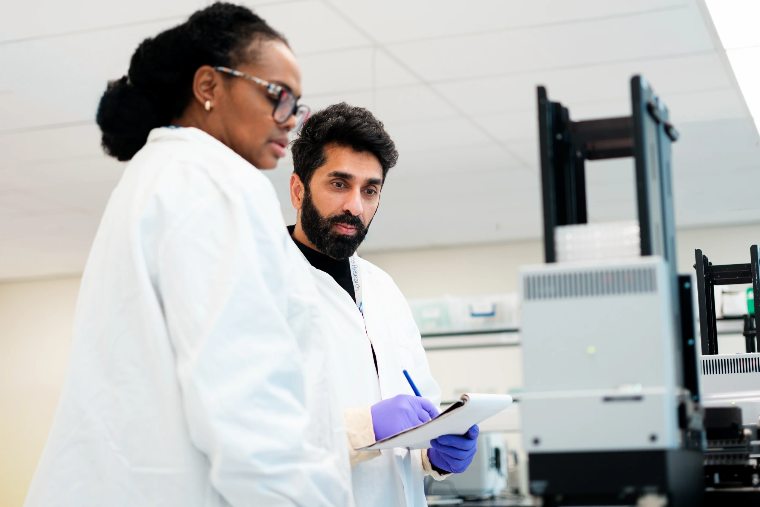 Scientists discussing laboratory workflow beside instrumentation