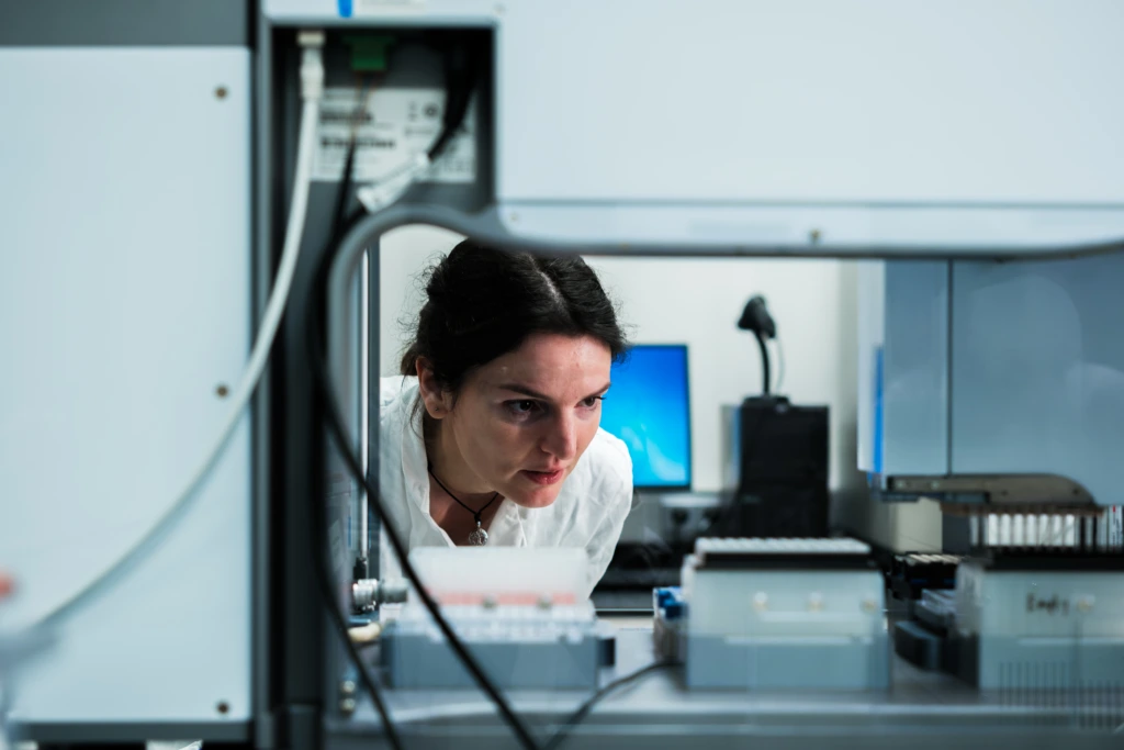 Scientist working beside automated laboratory instrumentation