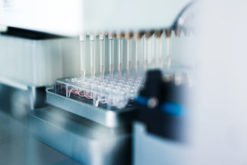 Close up automated pipette system dispensing into microplate