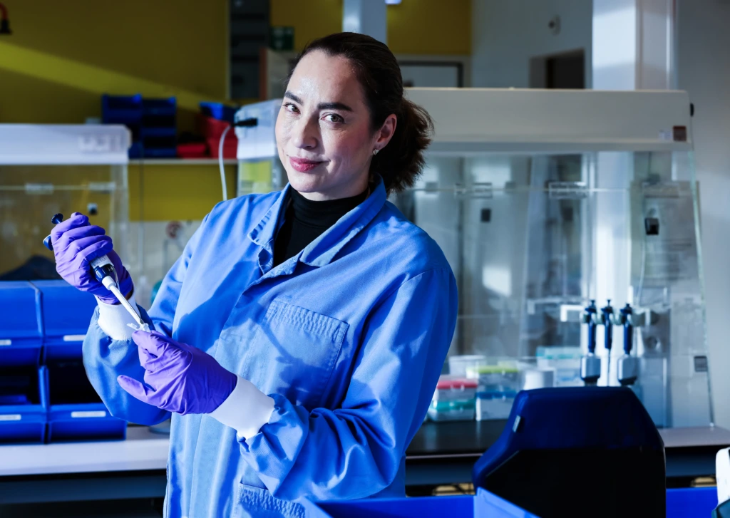 Medium close up of female scientist in blue coat at laboratory instrument