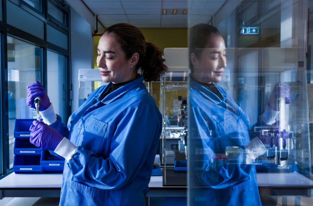 Medium shot of female scientist in blue coat at laboratory equipment