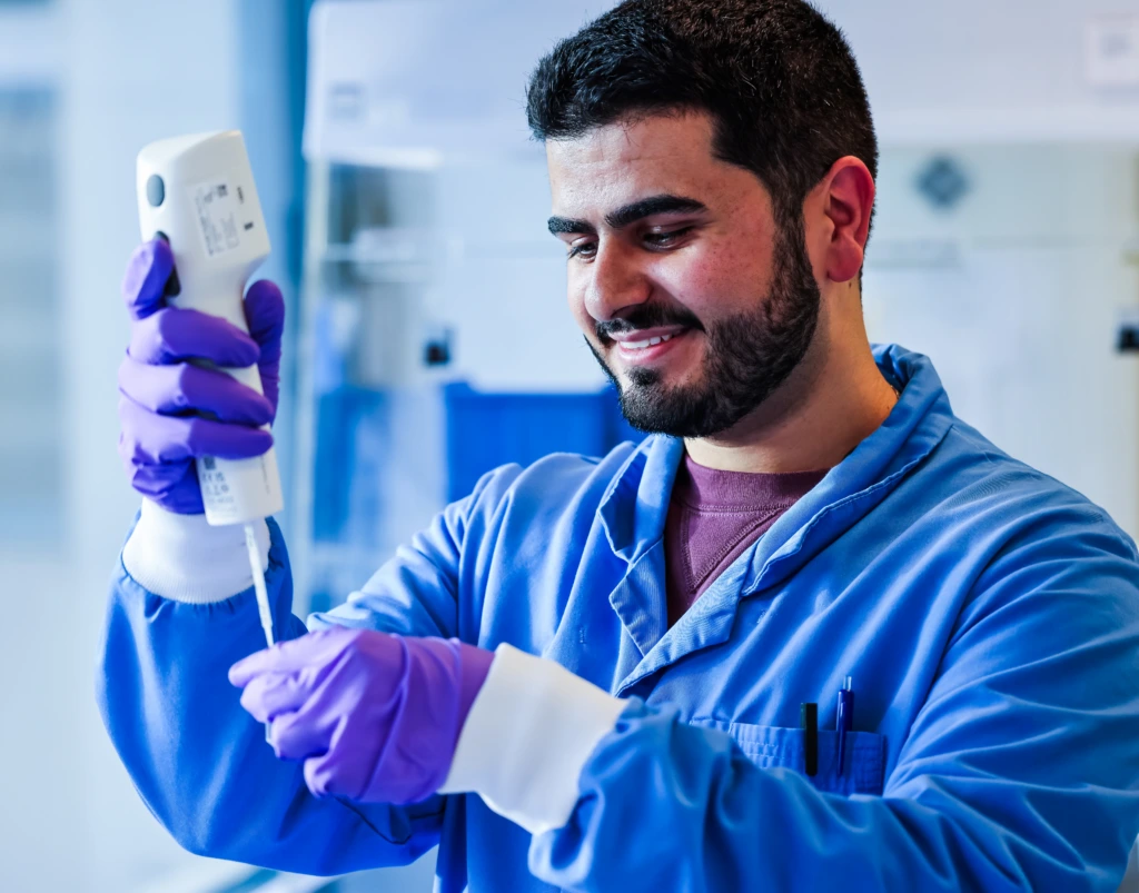 Medium close up portrait of male scientist in blue coat holding sample