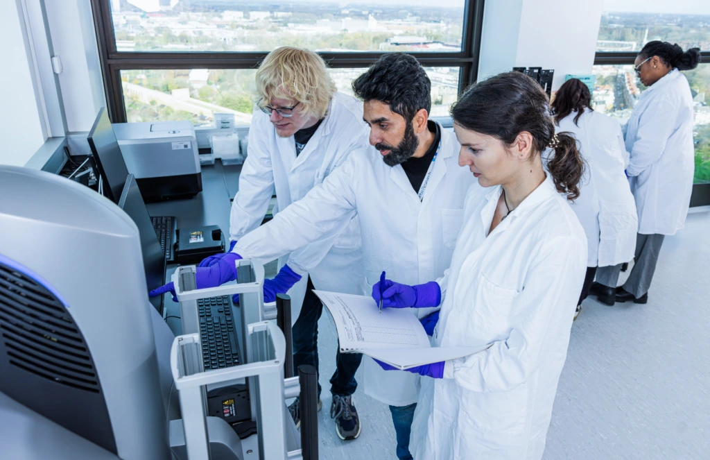 Wide shot of group of scientists collaborating at laboratory workstations