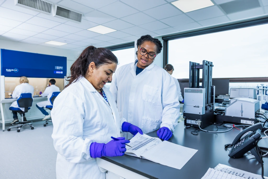 Wide shot of scientists working at bright laboratory workstations