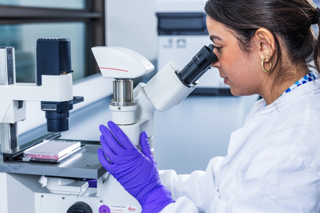Medium close up of female scientist looking through laboratory microscope