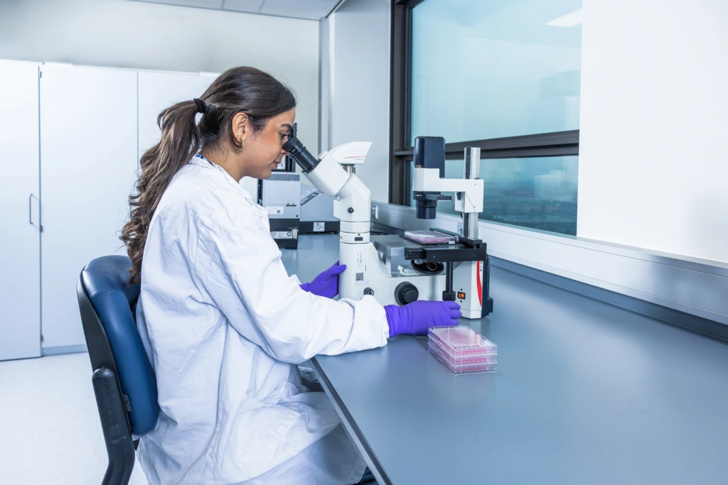 Medium shot of female scientist seated at laboratory microscope