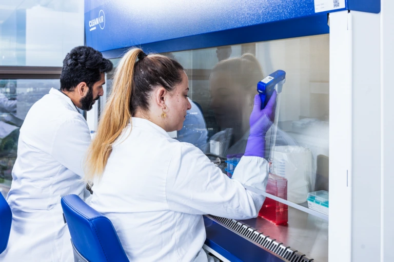 Medium shot of female scientist working at a bright biosafety cabinet