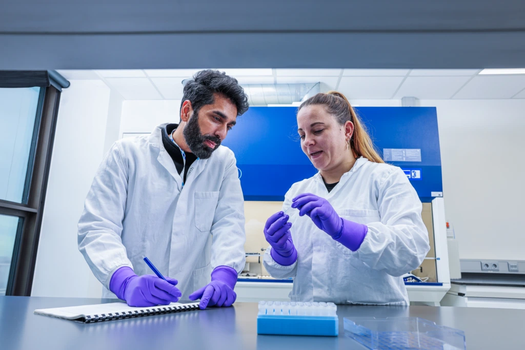 Medium shot of two scientists smiling and collaborating at laboratory bench