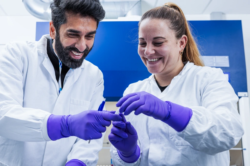Medium shot of two scientists smiling while working with laboratory samples