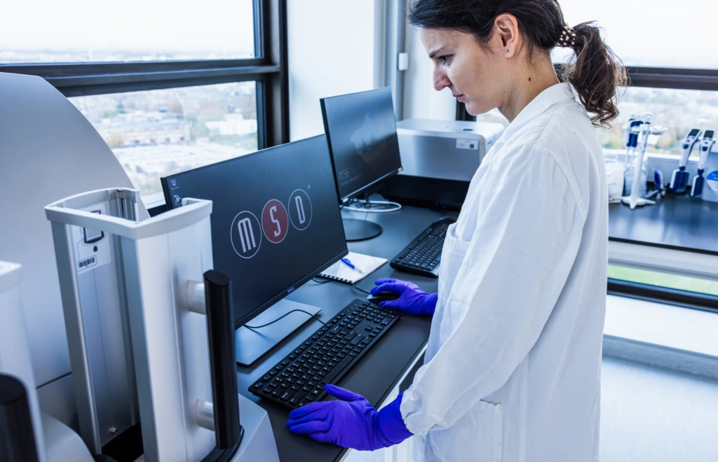 Medium shot of female scientist standing before laboratory analyser equipment