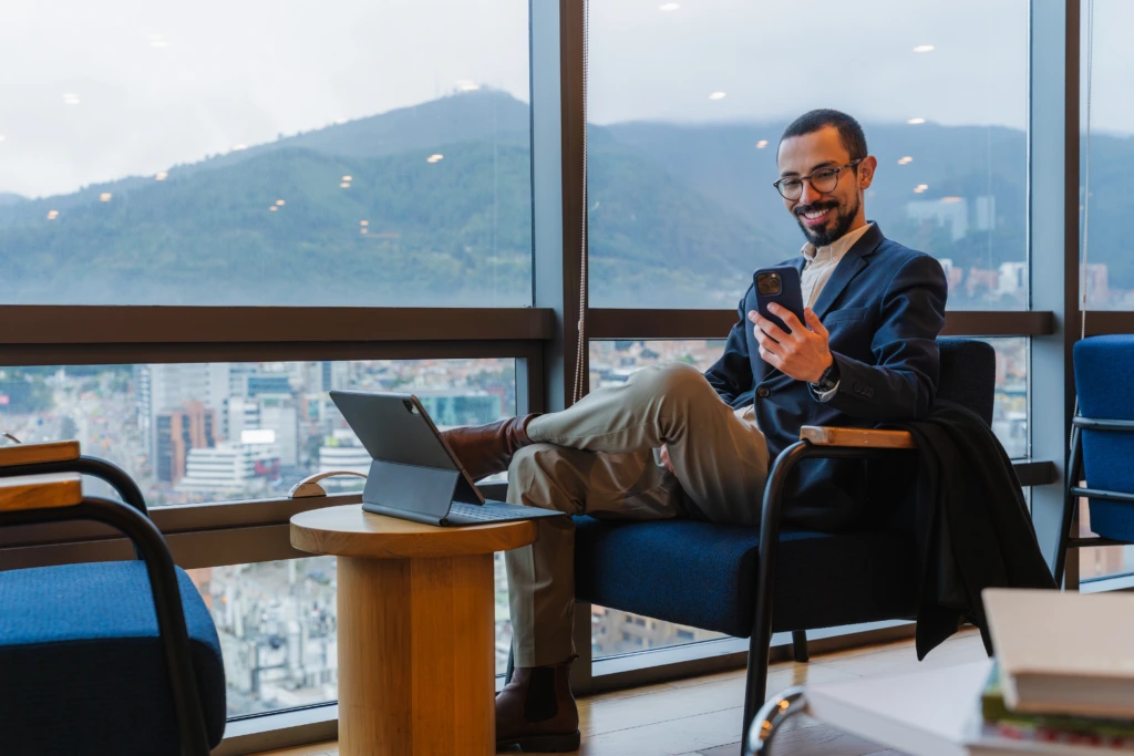 Man,Smiling,While,Checking,Phone,And,Relaxing,In,A,Corporate